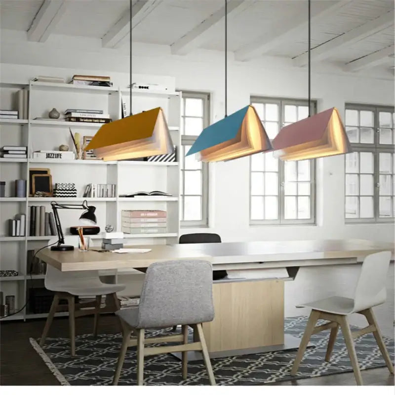 Three modern colorful book pendant lamps with layered paper design in mustard yellow teal blue and dusty rose for living room decor