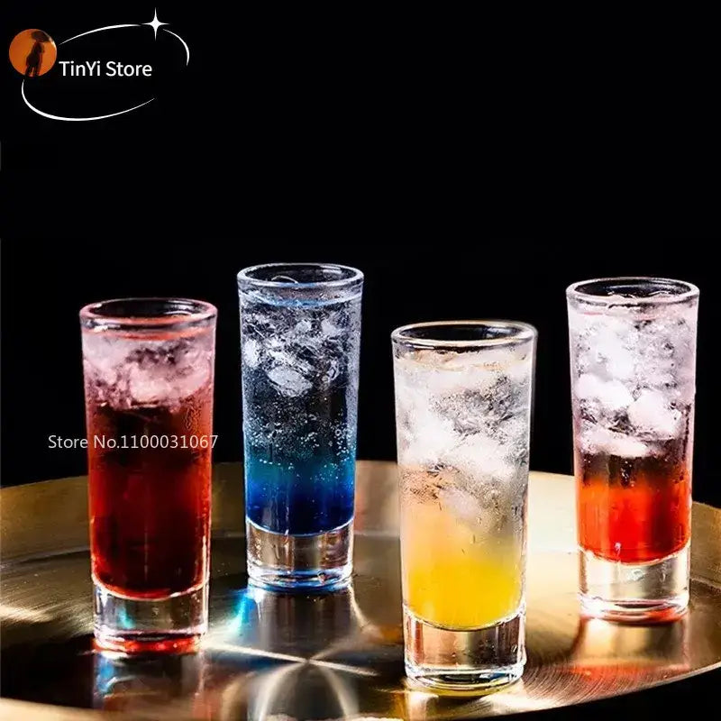 Four colorful decorbites bullet cocktail glasses filled with layered cocktails on a metallic kitchen tray
