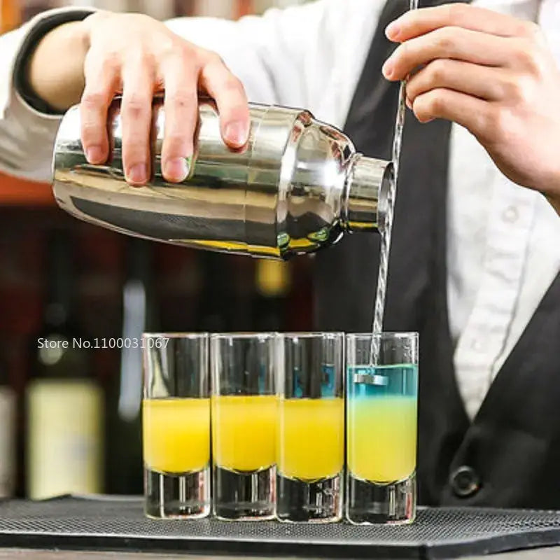 Shiny stainless steel cocktail shaker pouring into four colorful bullet cocktail glass set for kitchen tray decorbites bullet cocktail