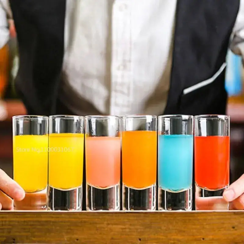 Six clear glass decorbites bullet cocktail glasses filled with vibrant liquids in a colorful cocktail glass set