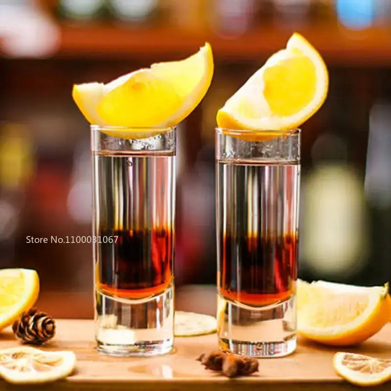 Two clear glass bullet cocktail glasses with layered drinks and lemon wedges from decorbites cocktail glass set of 6