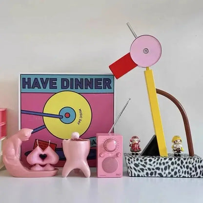 Pink vintage-style portable radio with circular dial and speaker grille next to colorful cartoon led floor lamp for living room lighting