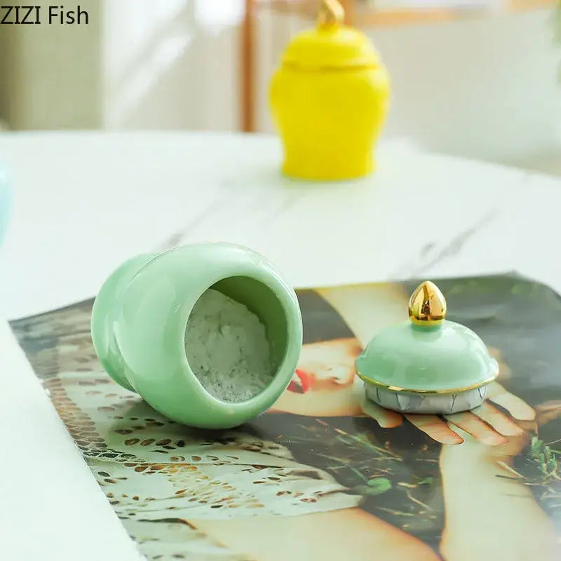 A mint green ceramic storage jar with gold-tipped lid and silver trim for kitchen tea caddy use