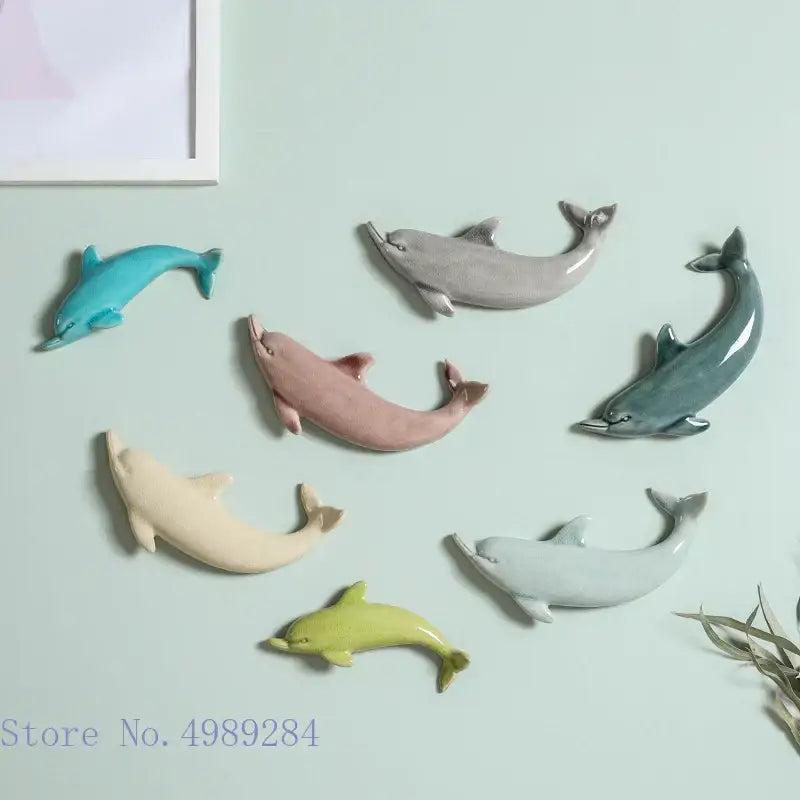 Set of seven pastel-colored ceramic dolphins in teal gray pink cream light green and pale blue wall decoration for children’s room
