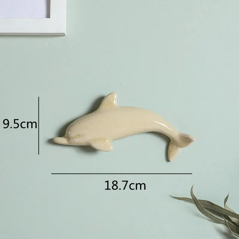 Cream-colored ceramic dolphin fish ocean wall decoration measuring 9.5cm tall and 18.7cm long for children’s room