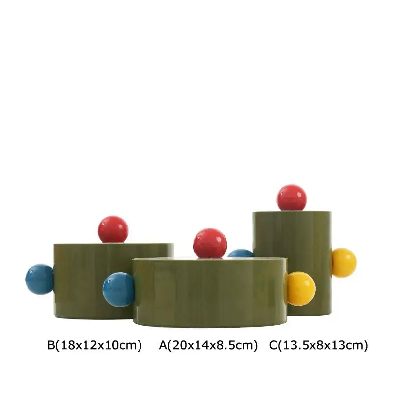 Olive-green cylindrical storage jar with colorful dot decorative accents in red blue and yellow for bedroom organization