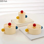 Cream-colored cylindrical storage jar with colorful dot decorative handles and red lids by zizi fish for bedroom organization