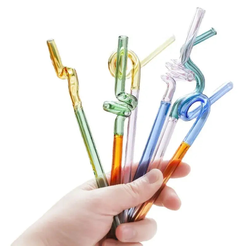 A hand holds colorful glass flower handle stir bars with twisted and coiled designs for kitchen cocktails