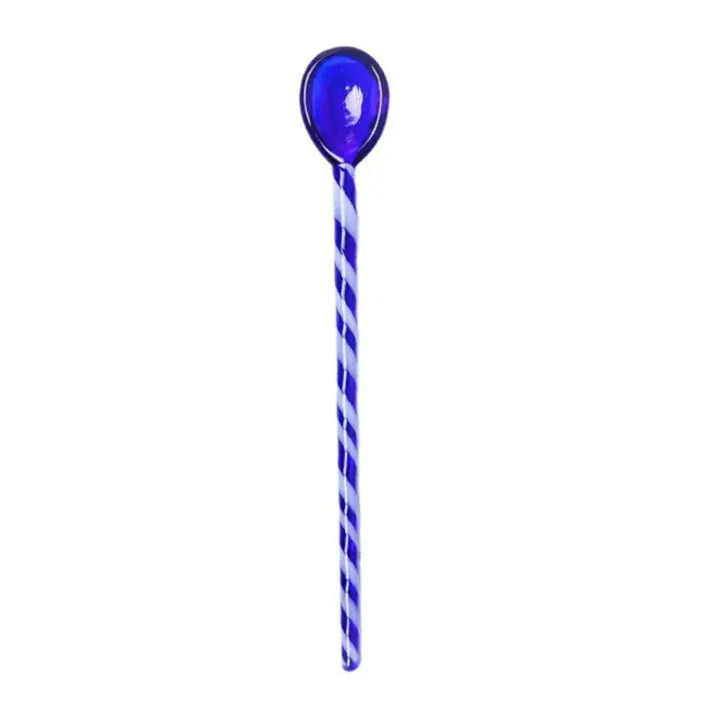 A translucent cobalt blue colorful glass stirring spoon with a twisted white and blue striped handle by decorbites colorful glass