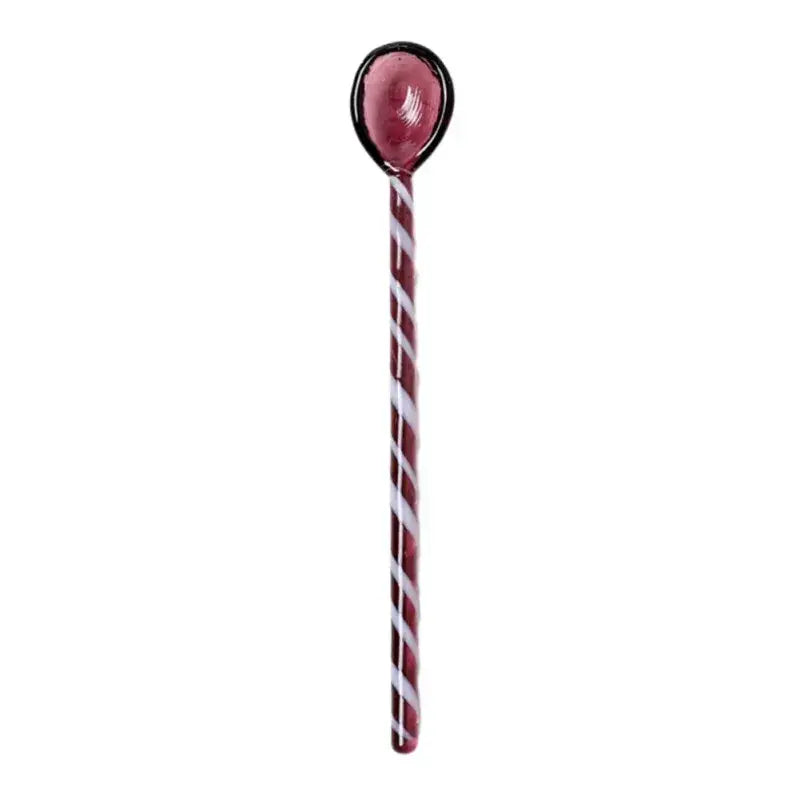 A deep red candy cane shaped colorful glass stirring spoon with white spiral stripes and a black rimmed oval top from decorbites colorful glass