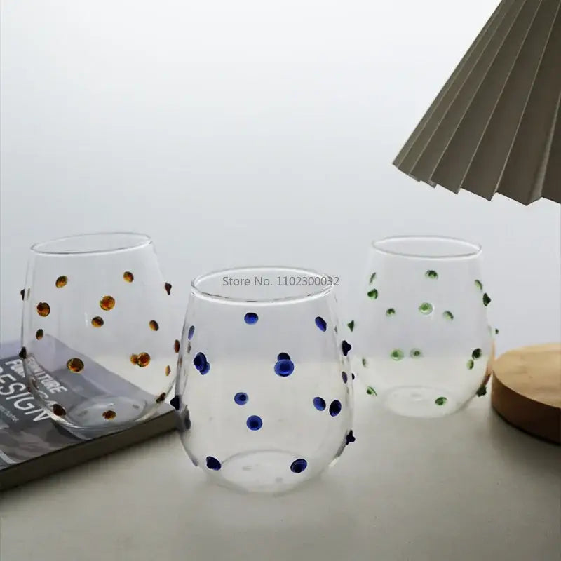 Three clear stemless wine glasses with hand-painted gold blue and green glass wave dots for dining room use
