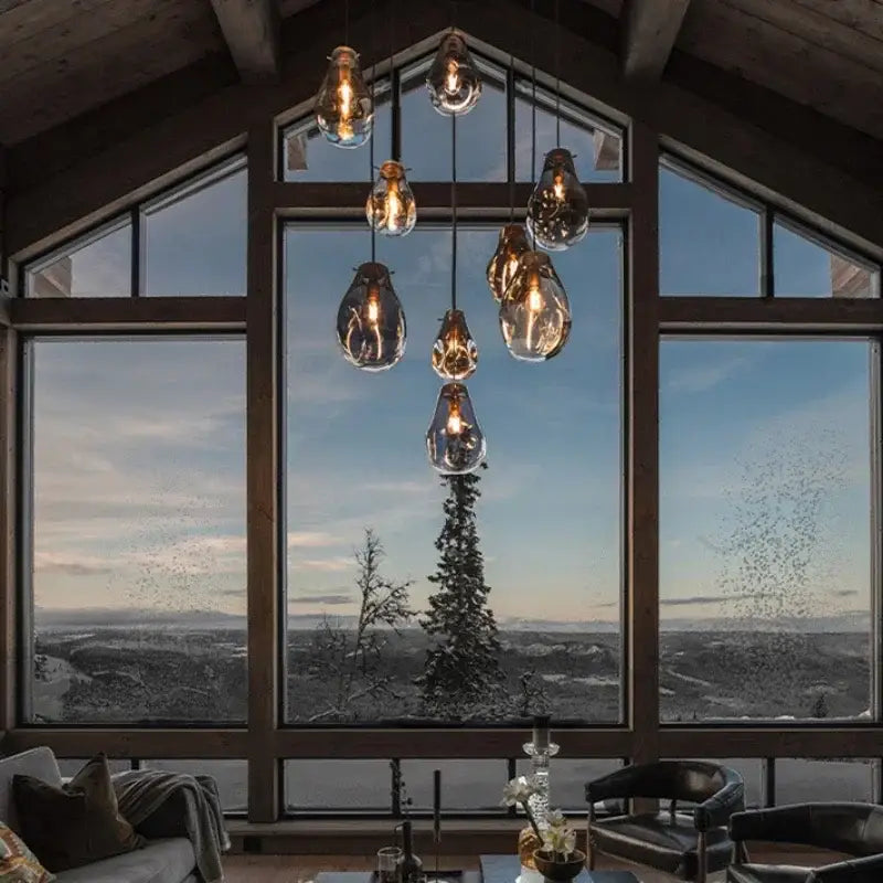 A cluster of warm-toned colorful modern glass pendant lights with exposed filament bulbs for dining room decorbites