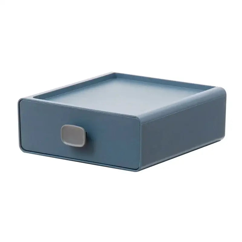 A sleek matte blue plastic desktop cosmetic storage box with minimalist design and gray pull handle by decorbites