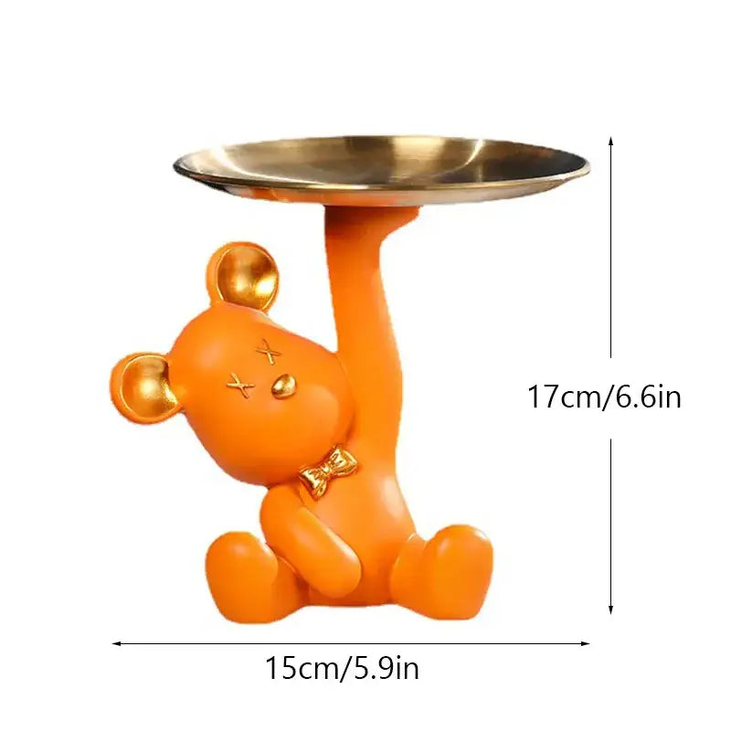 Orange resin bear house entry tray keys receiver with gold accents holding a metallic tray for living room use