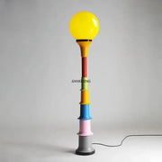 Colorful retro led floor lamp with vibrant multi-colored stacked cylinders and bright yellow spherical bulb for bedroom decorbites