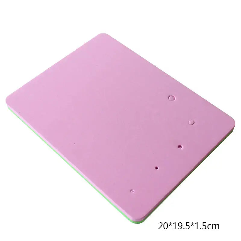 Pink rectangular silicone cake shaping mat with rounded corners and green underside featuring four small indentations