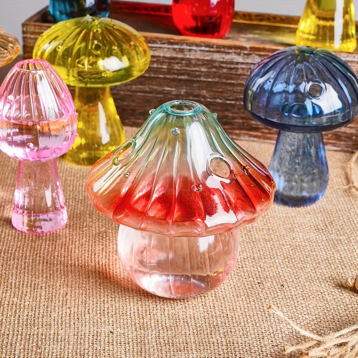 A translucent red and pink gradient glass mushroom-shaped aromatherapy vase with ribbed cap and clear base for decoration