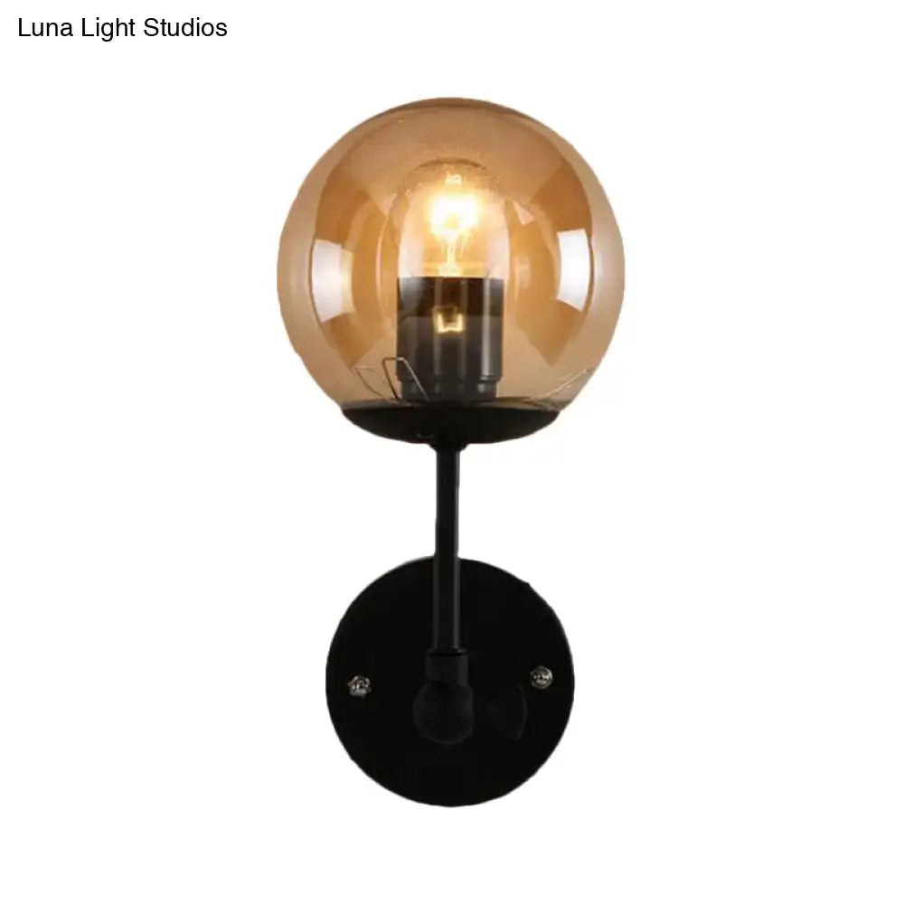 Contemporary wall light with warm amber globe glass shade and black metal base featuring exposed filament bulb for bedroom