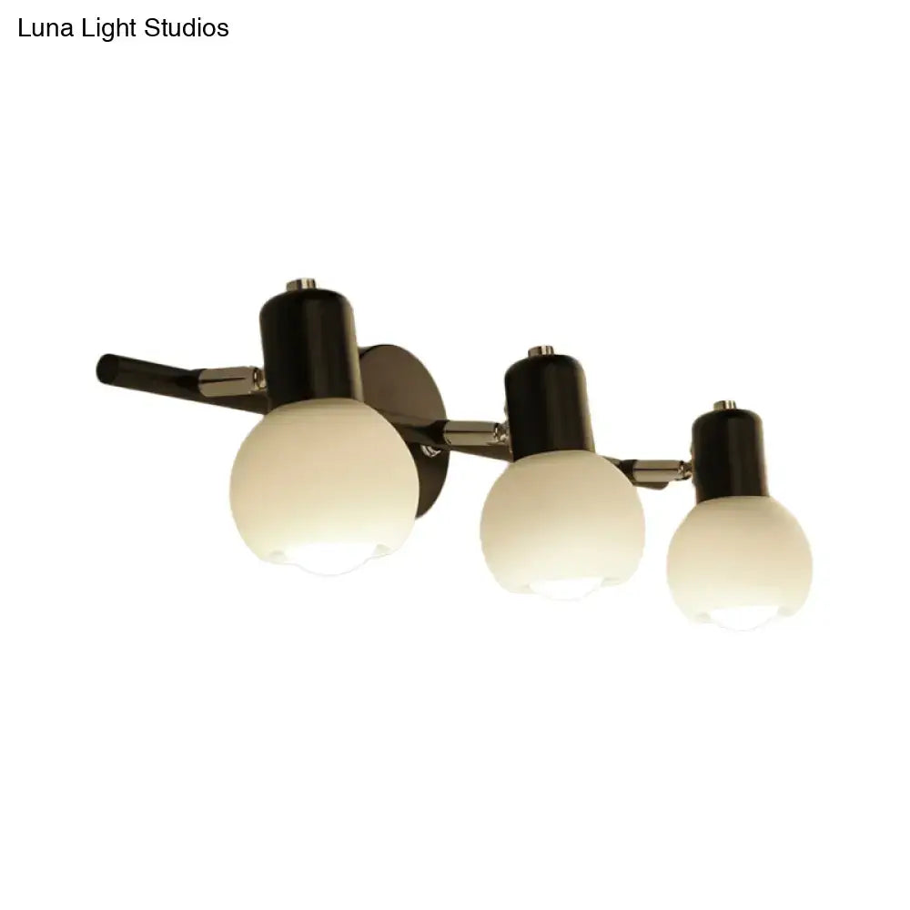 Contemporary black and chrome wall-mounted sconce with three frosted milk glass globe shades for living room lighting