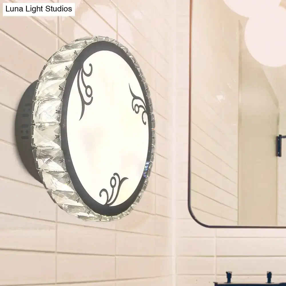 Contemporary black circular wall light with clear crystal trim and decorative swirls on frosted glass face for bedroom