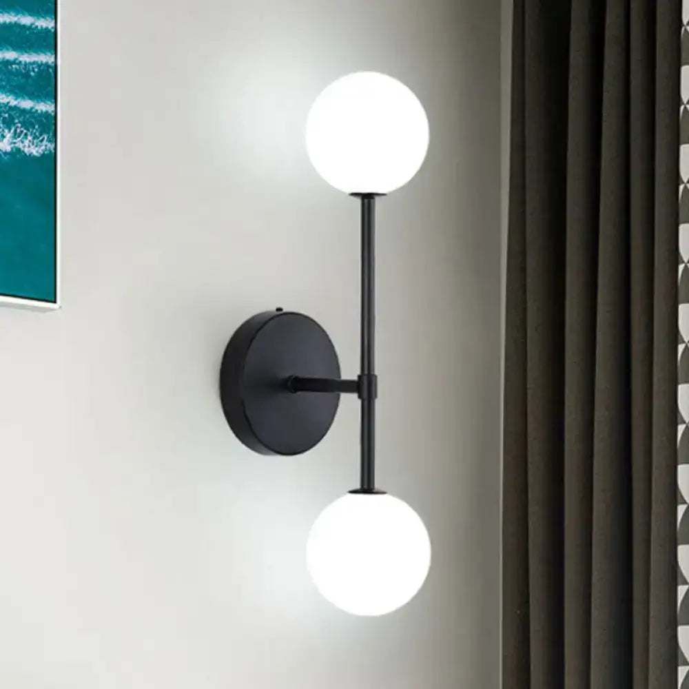 Contemporary black and gold dual ball wall lamp with two glowing white spherical bulbs for bedroom use inch fixture