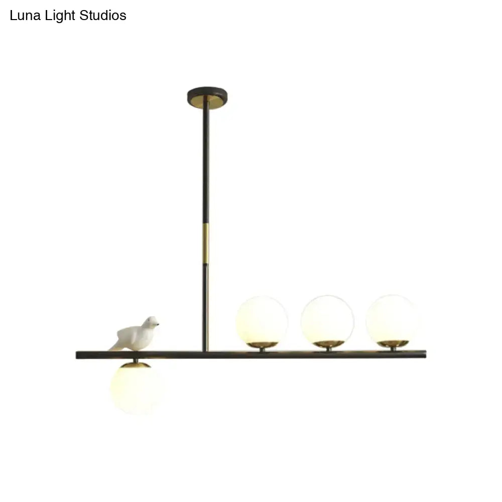 DecorBites contemporary linear branch dining pendant light in black and brass with cream glass bulbs and ceramic bird decor