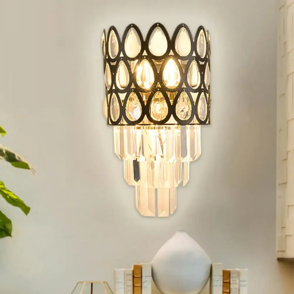 Contemporary black gold sconce with teardrop crystals features a black metal frame and cascading glass prisms for living rooms