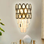 Contemporary black gold sconce with teardrop crystals features a black metal frame and cascading glass prisms for living rooms