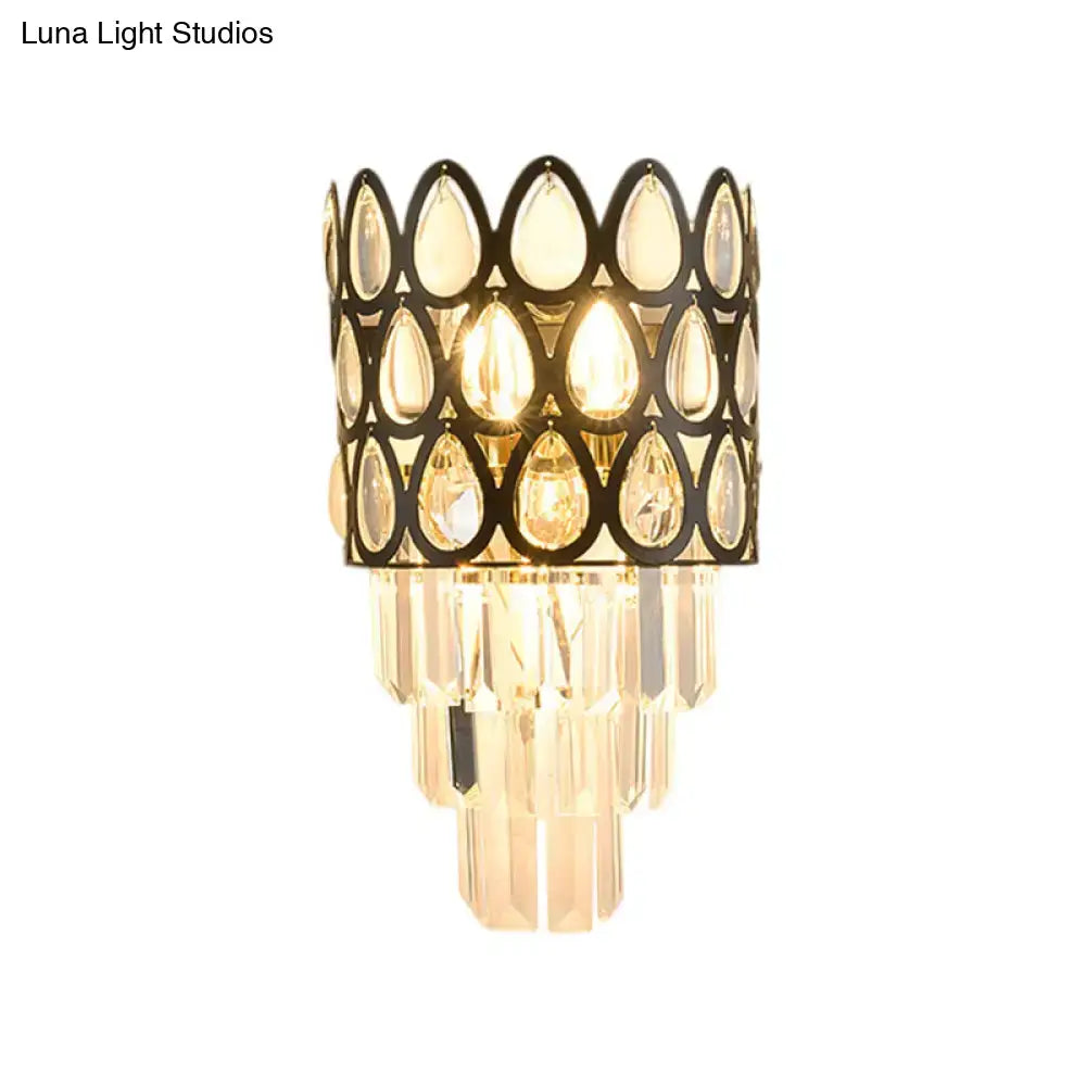 Elegant black gold sconce with teardrop crystals and clear glass prisms lighting living room with grid wall mount
