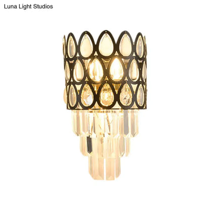 Elegant black gold sconce with teardrop crystals and clear glass prisms lighting living room with grid wall mount