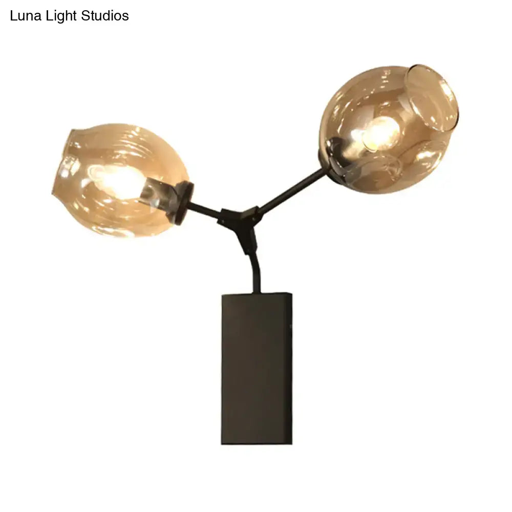 Contemporary black and gold wall sconce with modern black metal frame and amber clear glass shade for light wall decor