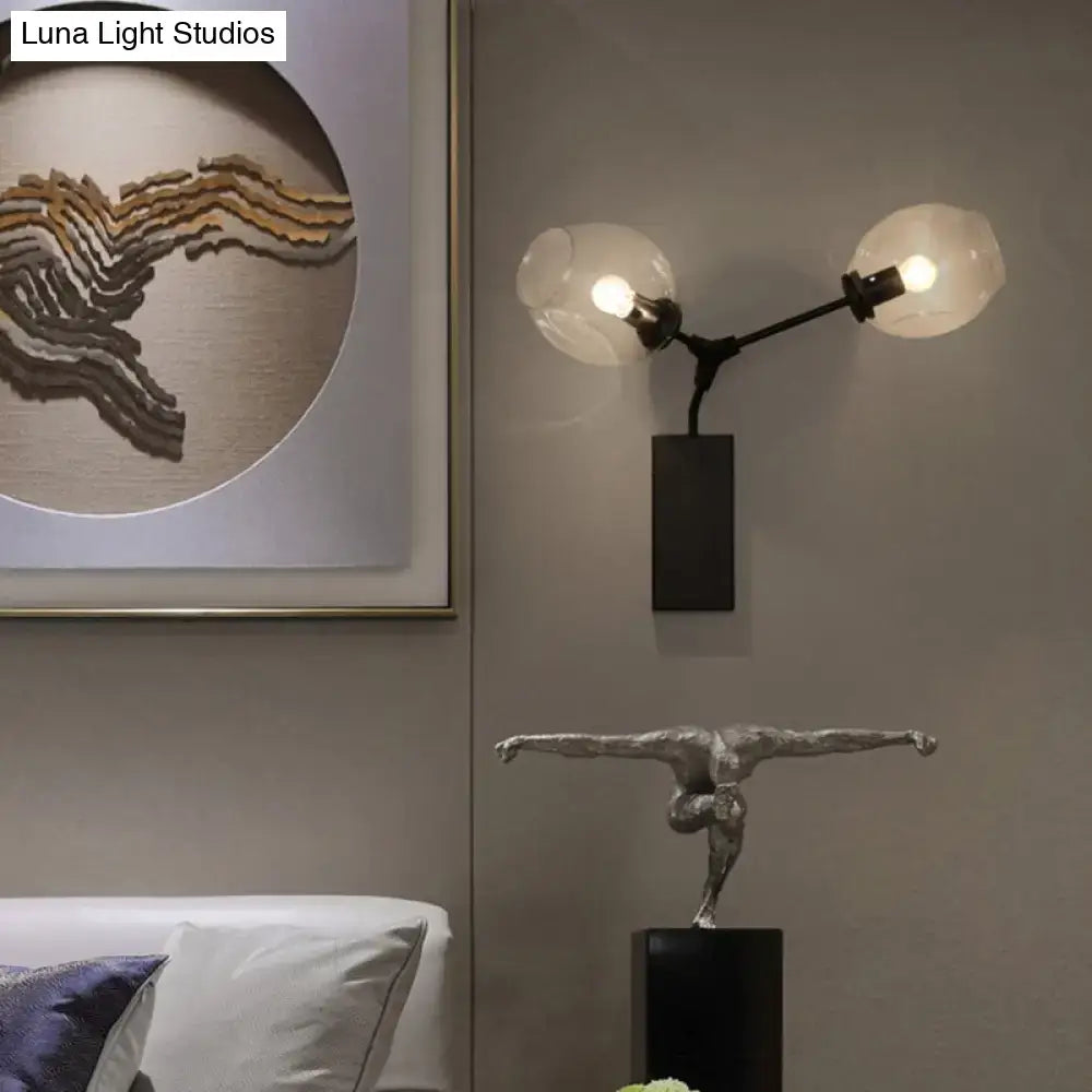 Silver metallic sculpture in mid-air pose on black base displayed beside a contemporary black and gold wall sconce with clear glass shade