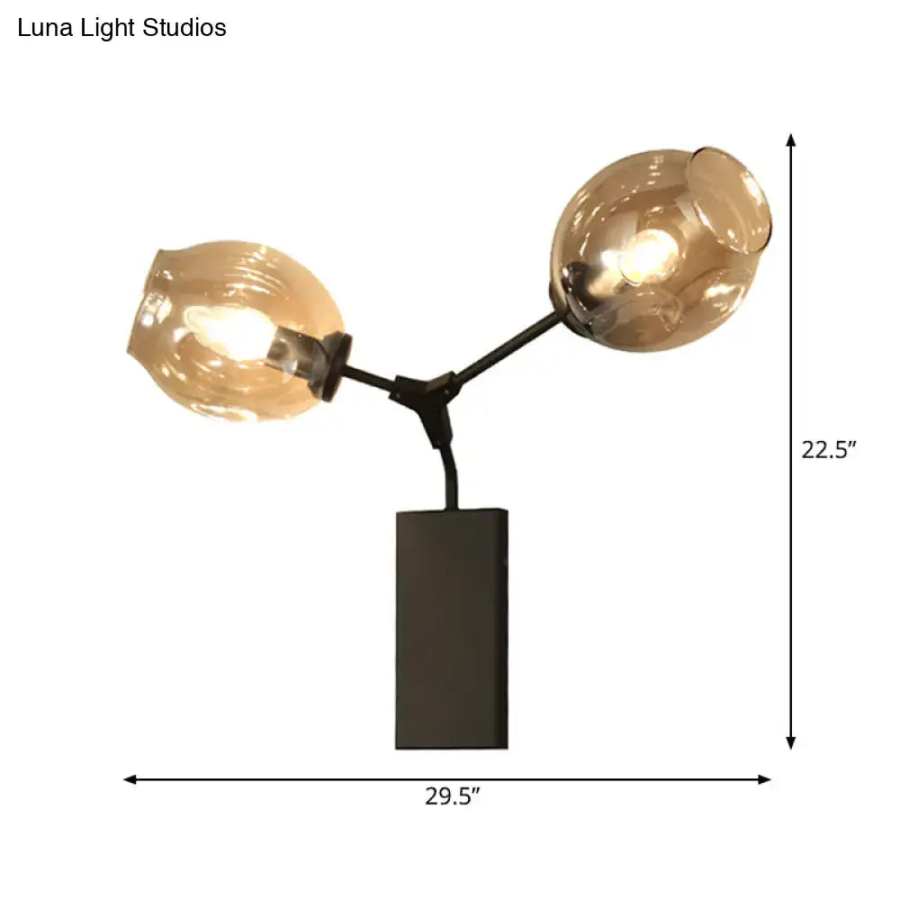 Modern black metal table lamp with two amber glass globes paired with a contemporary black and gold wall sconce clear glass shade