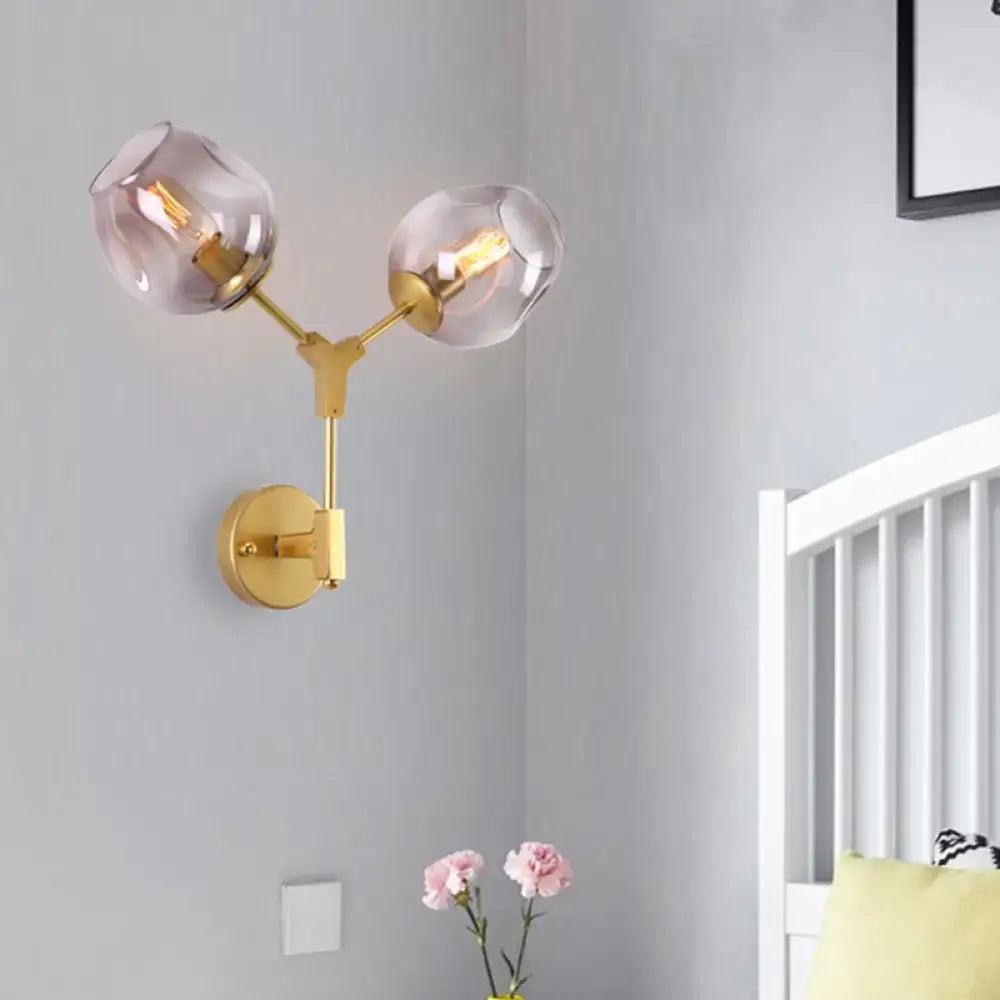 Contemporary gold-toned wall sconce with two frosted globe shades and clear glass shade for bedroom light wall use