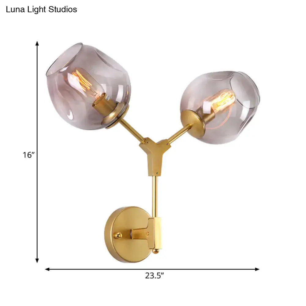 Contemporary black and gold wall sconce with gold-toned frame, clear glass shade, and exposed filament bulbs