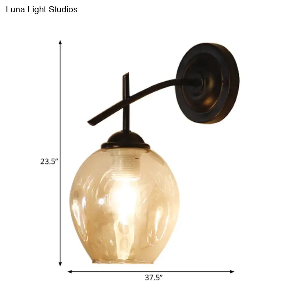 Contemporary black and gold wall sconce with warm amber glass globe and dark bronze arm featuring a clear glass shade