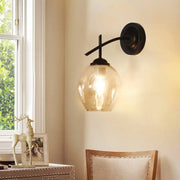 Contemporary black wall sconce with warm-toned clear glass shade and black metal arm for modern light wall decor