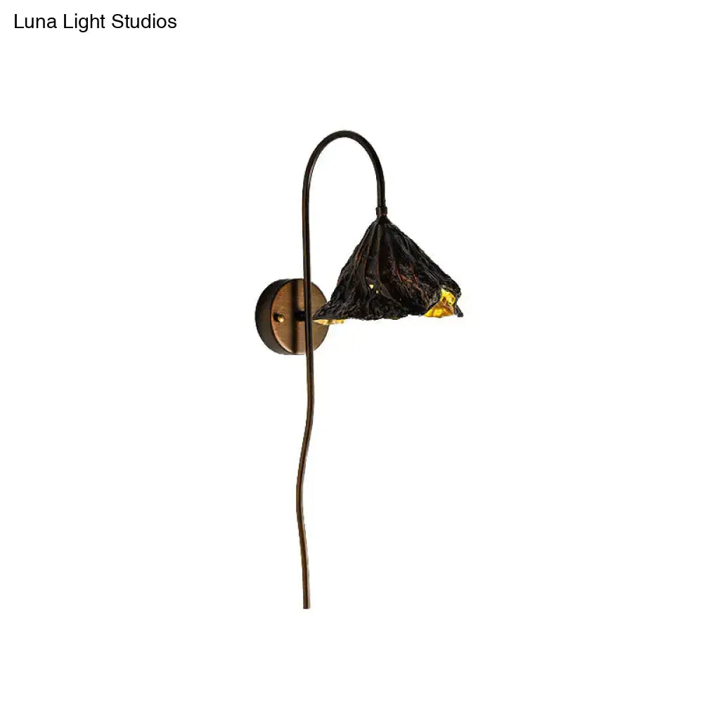 Contemporary black wrought iron wall light with textured lotus leaf glass shade and amber interior glow for living room