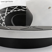 Contemporary black and white geometric wall lamp with circular x-pattern design for living room decor