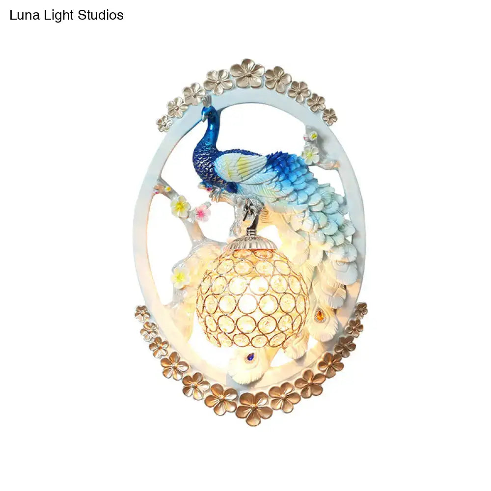 Decorative living room wall sconce with blue and white peacock and glowing crystal ball encased in gold lattice