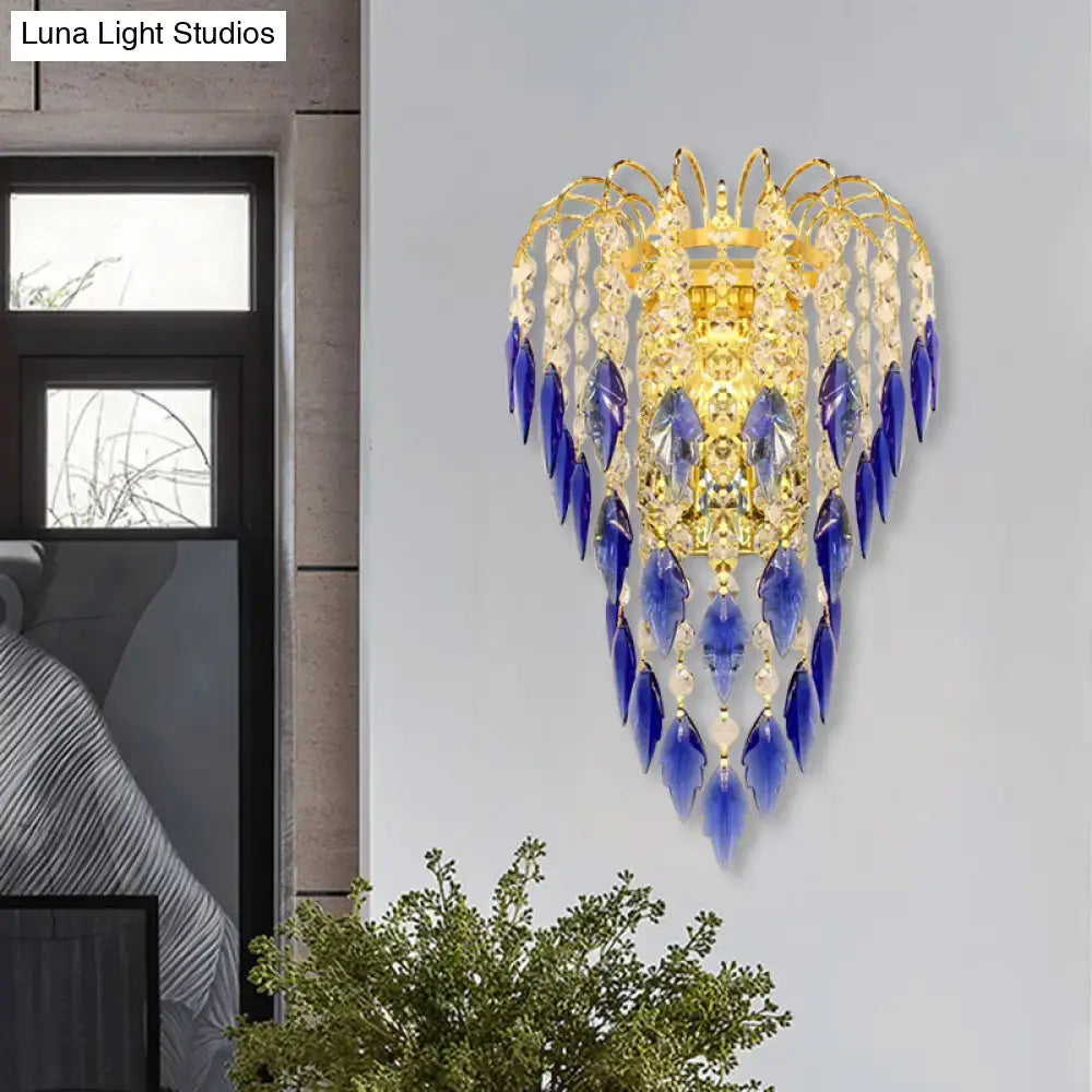 Elegant brass wall light with tan blue and clear crystal teardrops providing extra light for bedroom use