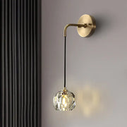 A contemporary brass wall light with crystal shades and voltage settings featuring a faceted globe on black cord