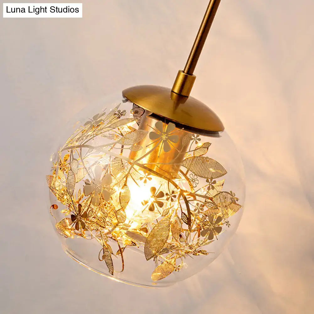 Contemporary brass clear glass wall lamp with foil flower decor featuring a spherical pendant and intricate gold etchings