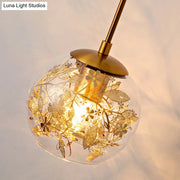 Contemporary brass clear glass wall lamp with foil flower decor featuring a spherical pendant and intricate gold etchings