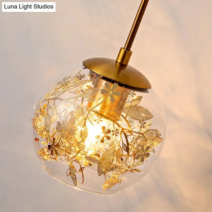 Contemporary brass clear glass wall lamp with foil flower decor featuring a spherical pendant and intricate gold etchings