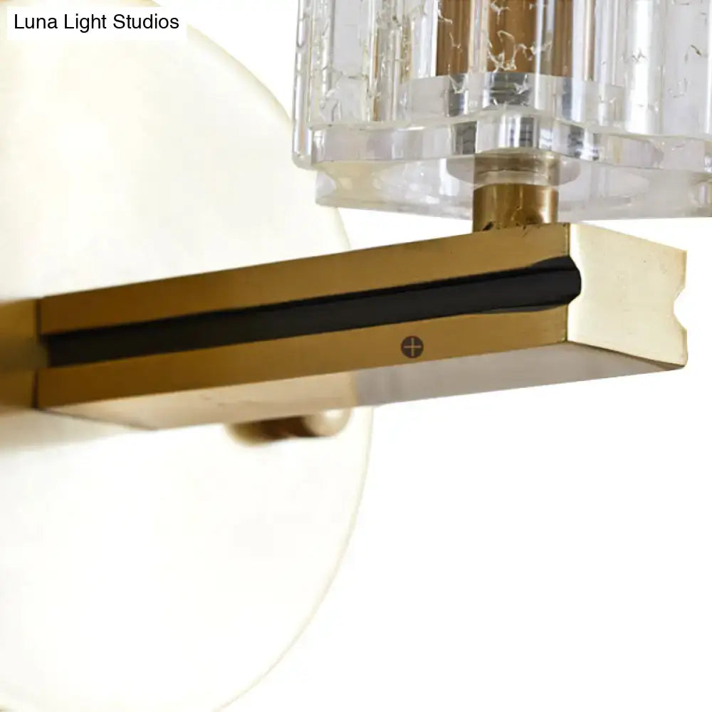 Contemporary brass crystal cylinder sconce light with gold-toned brass hardware and prismatic crystal cylinder shade for bedroom wall mount