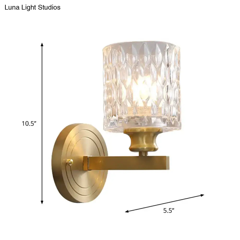 Contemporary brass cylindrical wall light with clear dimpled glass faceted shade for bedroom lighting