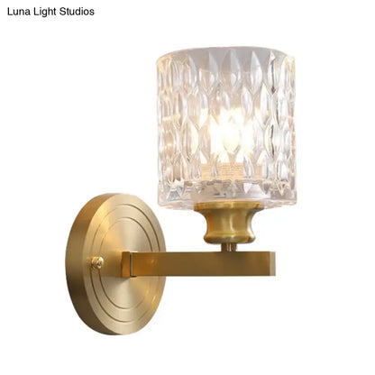 Contemporary brass cylindrical wall light with faceted clear dimpled glass shade for bedroom lighting