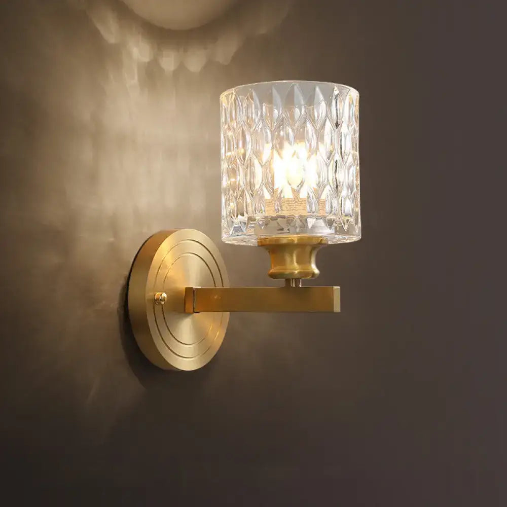 Contemporary brass cylindrical wall light with faceted clear dimpled glass shade for bedroom use