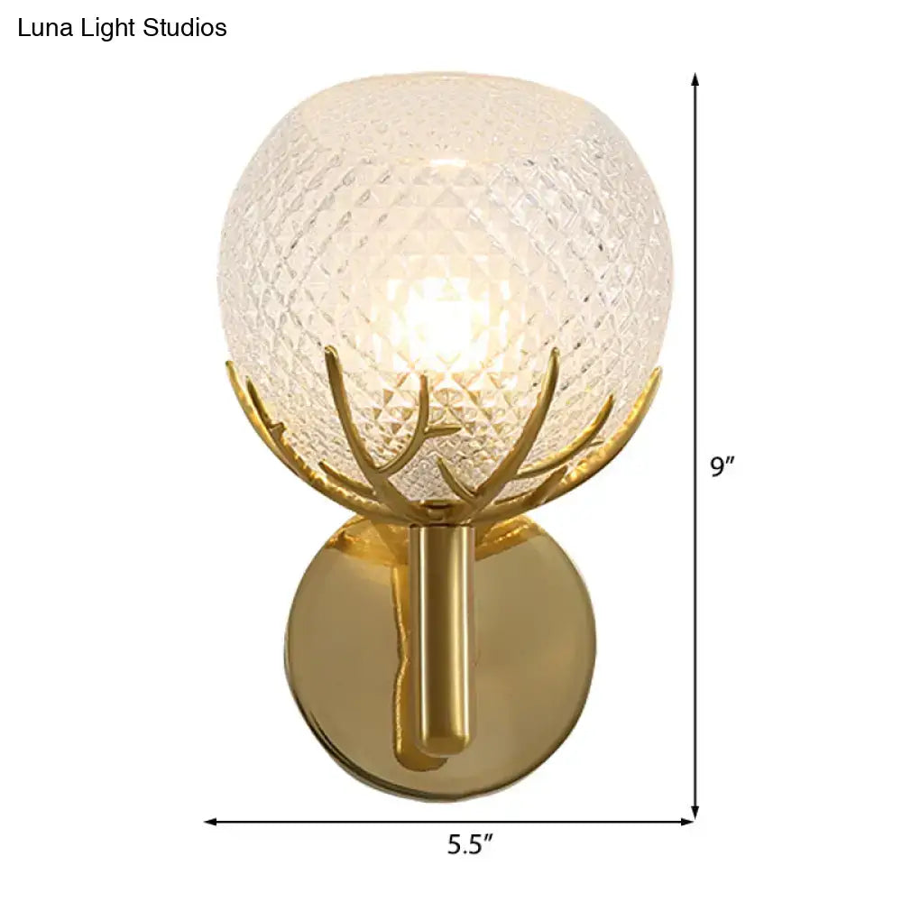 Contemporary gold-toned wall lamp with frosted lattice glass globe and antler-like metal accents for bedroom sconce